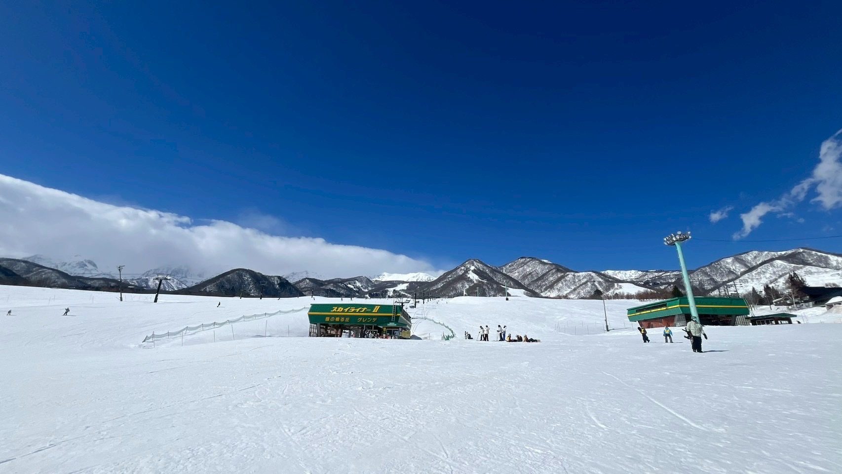 白馬栂池高原「鐘の鳴る丘」緩坡雪道與纜車站,背後是白馬的雪山
